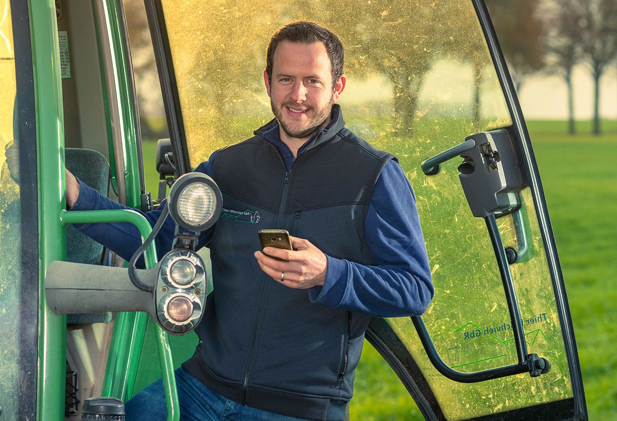 Landwirt mit Traktor und Handy auf Acker